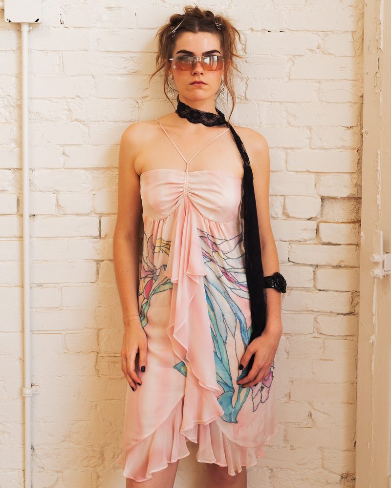 Grace now, in a pink dress against a white brick wall